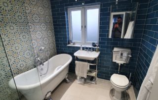 luxury bathroom featuring traditional fixtures paired with striking tiles by Top Grade build