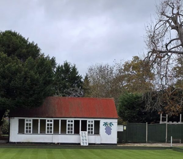 Screenshot the old crumbling bowling club building pavillion in white with a red roof
